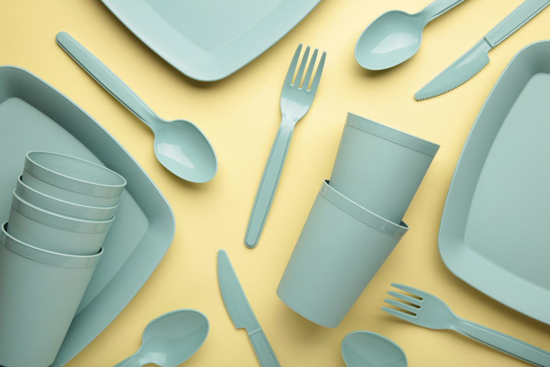 Bright plastic reusable tableware on a yelow background.